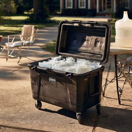 Large wheeled cooler open and filled with ice bricks on a suburban driveway