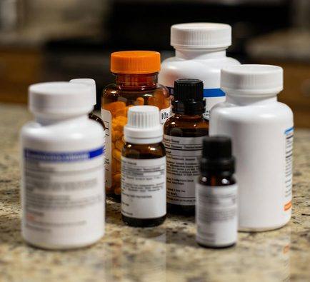 Multiple prescription pill bottles and medicine bottles arranged on a kitchen counter