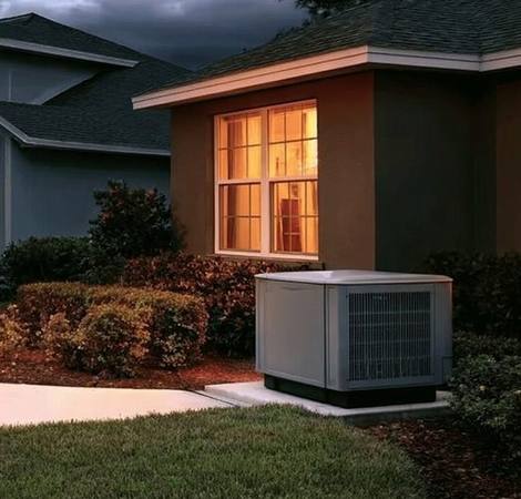 Whole-home standby generator on concrete pad beside house with propane tank at golden hour